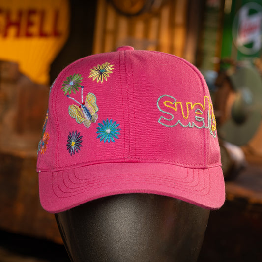 Pink cap with colorful butterfly and flower designs on a blurred background