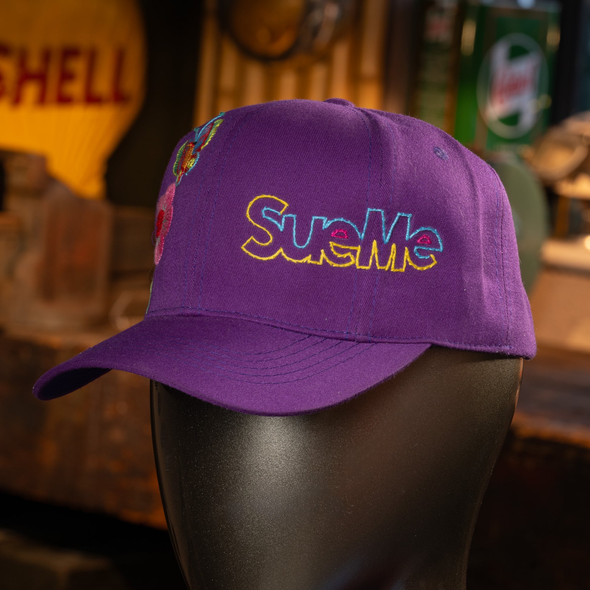 Purple cap with colorful text on a mannequin head against a blurred background