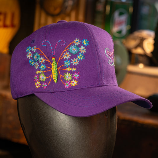 Purple cap with a colorful butterfly design on a mannequin head.