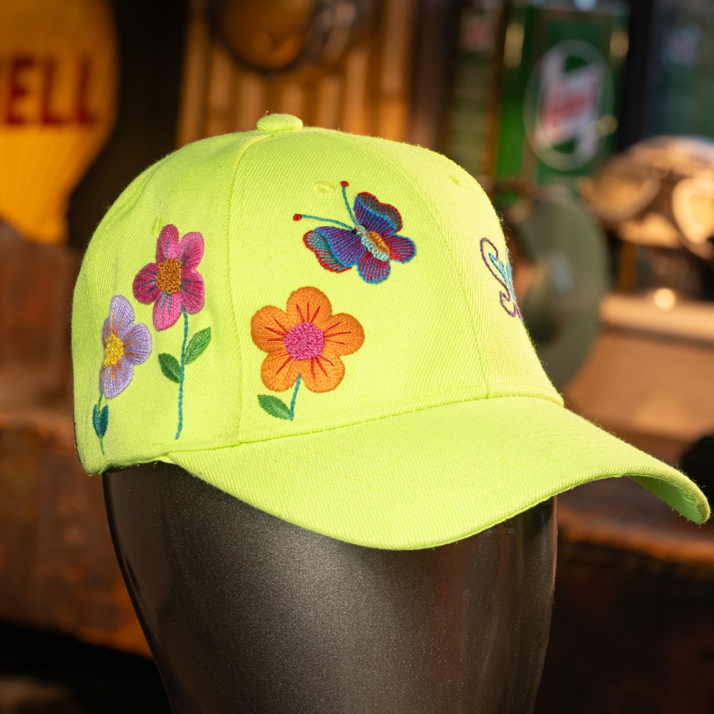 lime green with floral and butterfly designs on a mannequin head against a blurred background.