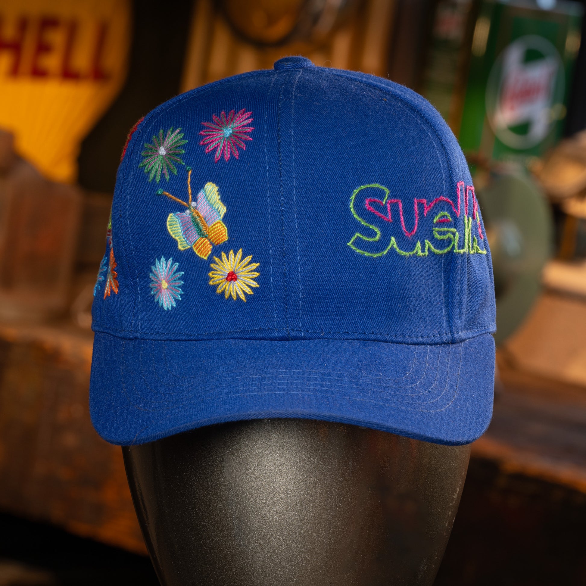 Blue cap with colorful embroidery on a mannequin head against a blurred background