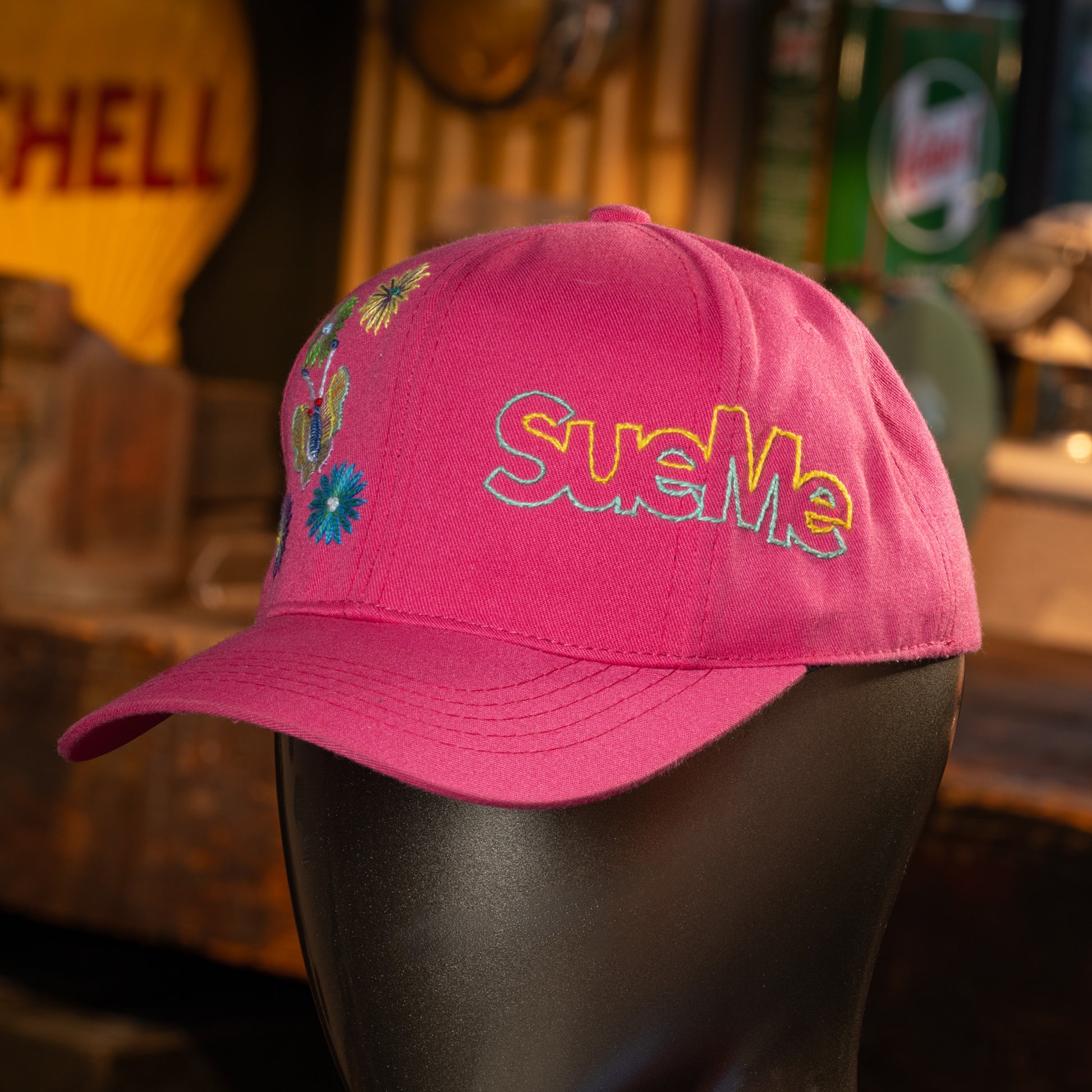 Pink cap with colorful embroidery on a mannequin head against a blurred background